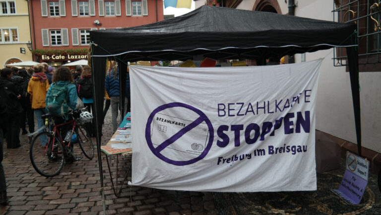 Zelt und Banner beim Protest gegen die Bezahlkarte am Freiburger Rathausplatz am 25. September 2025. Foto: Radio Dreyeckland (CC NC-SA 2.0)